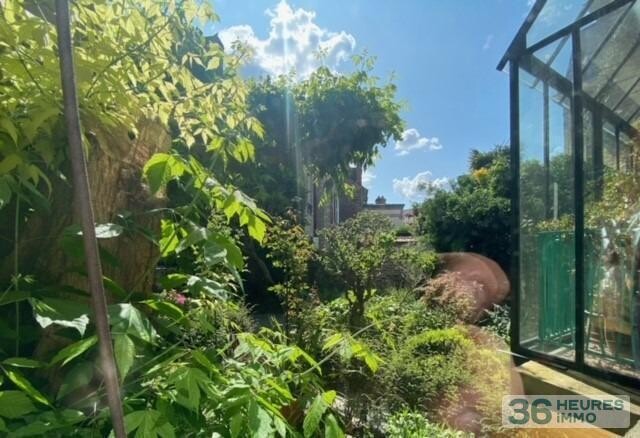 Maison de ville avec garage, nichée au fond d'un jardin ensoleillé.