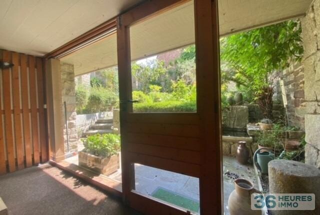 Maison de ville avec garage, nichée au fond d'un jardin ensoleillé.