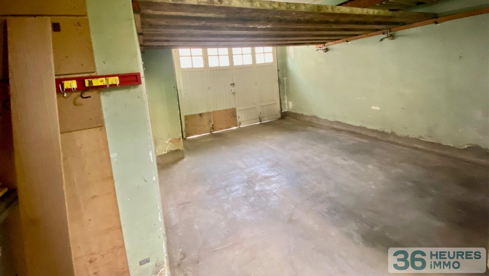 Maison de ville avec garage, nichée au fond d'un jardin ensoleillé.